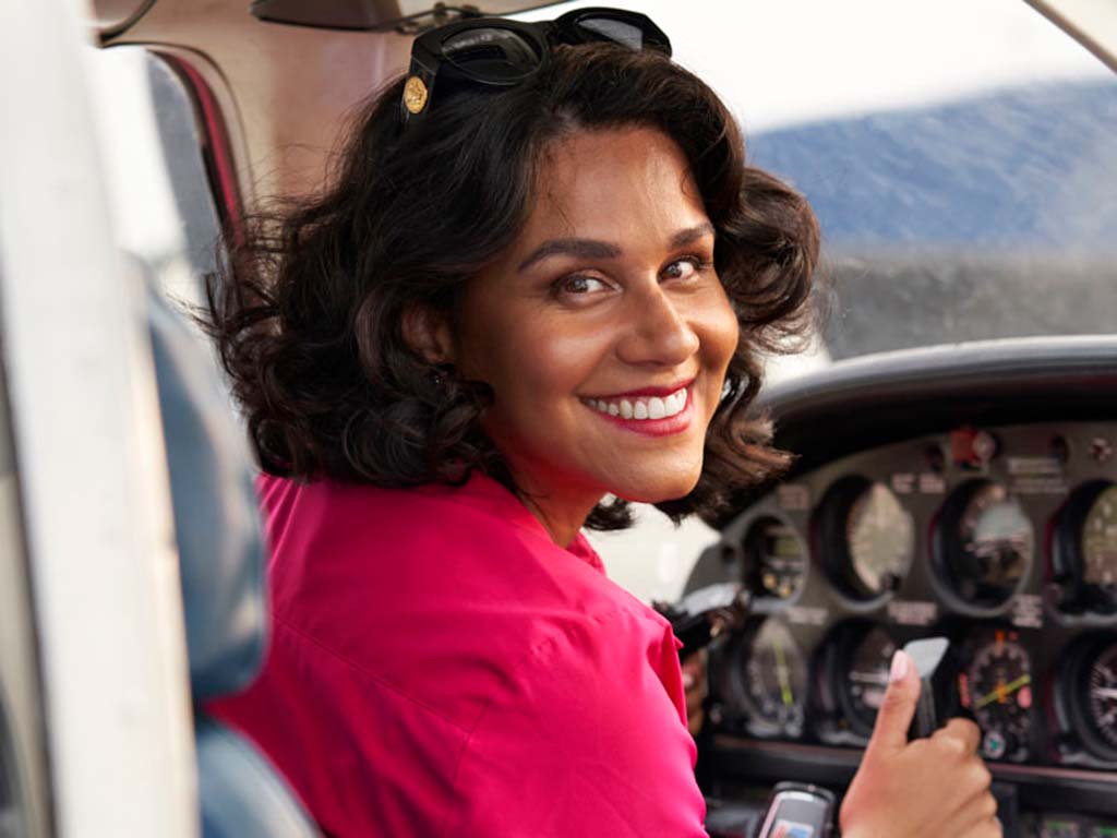 Sabrina Gomez Vila sits in the cockpit of an airplane smiling at the camera